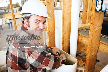 Plumber installing a toilet in a home which is under construction.