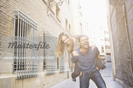 Tourist couple giving piggy back ride, Valencia, Spain