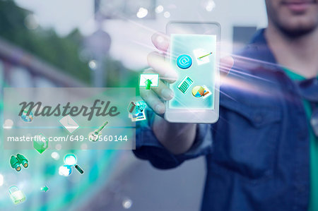Young man holding up smartphone with apps and icons coming out of it Young man holding up smartphone with apps and icons coming out of it