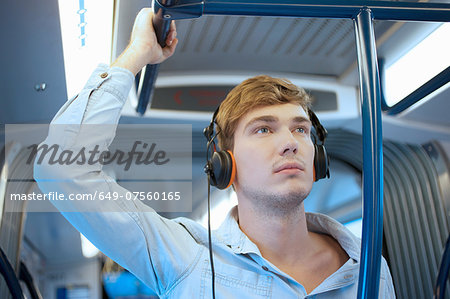 Young man in train carriage listening to headphones