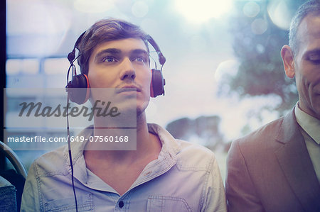 Young man daydreaming and listening to headphones on train