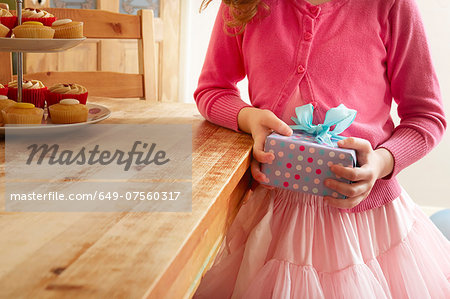 Girl holding birthday present, mid section