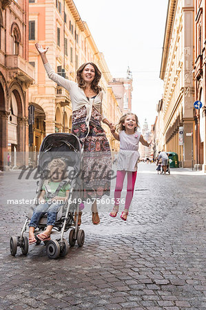 Mother and daughter, jumping in street, Bologna, Italy