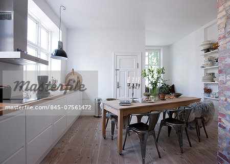 Open plan kitchen with wall shelving and window seat.