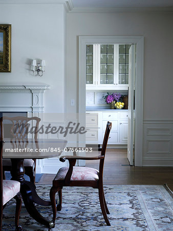Dark wood dining chair at table on patterned rug in Shelley Morris Designed Colonial style residence in New Canaan, Connecticut, USA