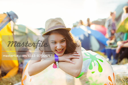 Portrait of smiling woman leaning on inflatable chair outside tents at music festival