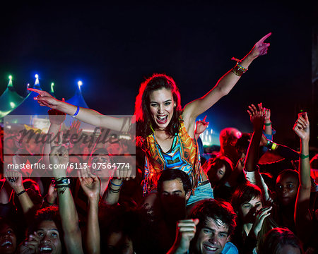 Cheering woman on man's shoulders at music festival Cheering woman on man's shoulders at music festival