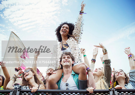 Cheering woman on man's shoulders at music festival