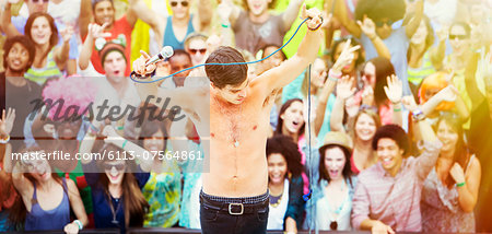 Performer dancing on stage with fans cheering in background at music festival