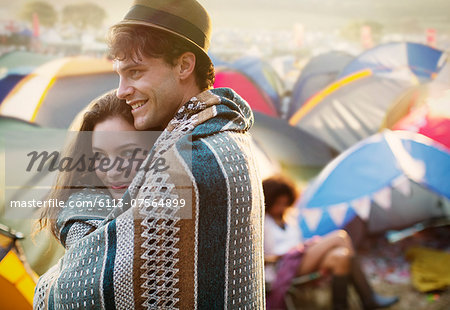 Couple wrapped in a blanket outside tents at music festival