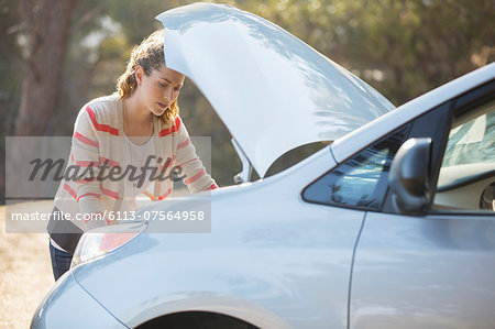 Woman checking car engine at roadside