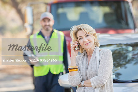 Roadside mechanic behind woman on cell phone