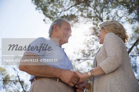 Happy senior couple holding hands under tree