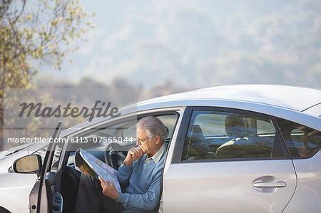 Senior man in car looking at map