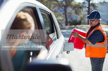 Woman watching roadside mechanic fill gas tank