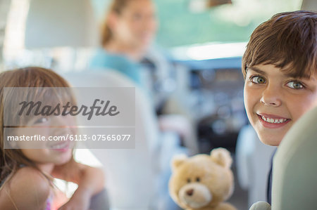 Portrait of happy brother and sister in back seat of car