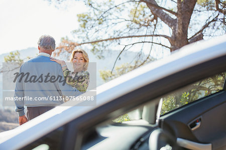 Senior couple hugging at roadside outside car