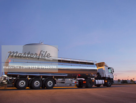 Stainless steel milk tanker next to silage storage tower