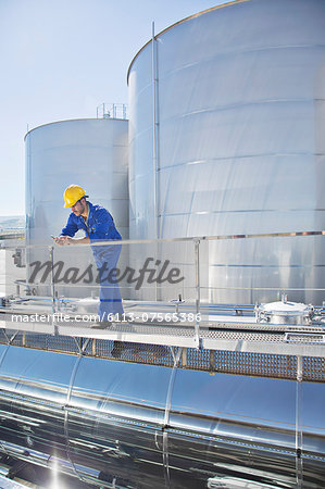 Worker using cell phone on platform above stainless steel milk tanker