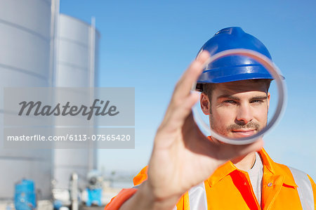 Portrait of worker looking through metal tube