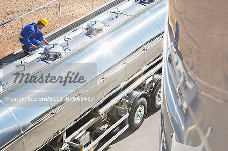 Worker on platform above stainless steel milk tanker