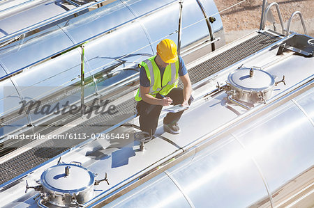 Worker using digital tablet on top of stainless steel milk tanker