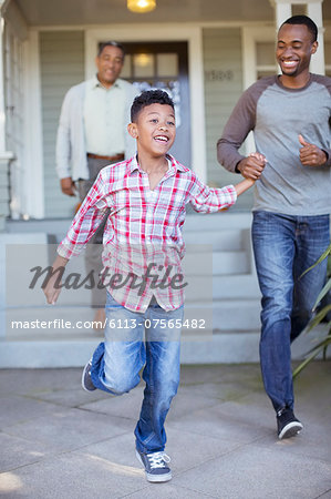 Father and son holding hands and running outside house