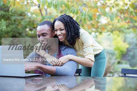 Happy couple using laptop at patio table