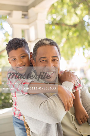 Close up portrait of smiling grandfather and grandson hugging on porch