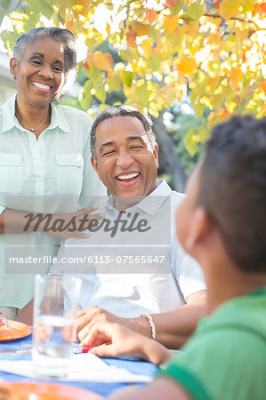 Grandparents and grandson laughing at patio table