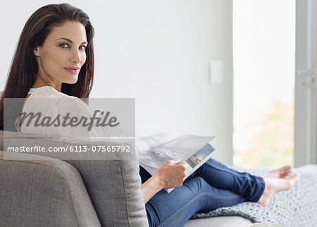 Portrait of confident woman reading magazine on chaise lounge