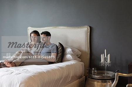 Couple using digital tablet in bedroom