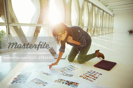 Creative businesswoman reviewing photography proofs on office floor