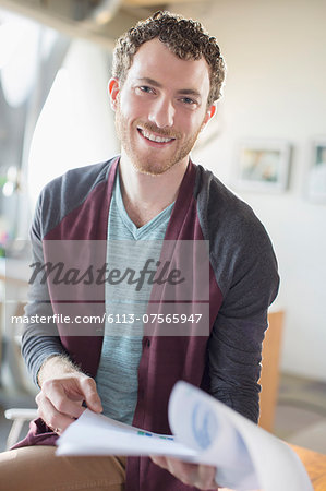 Portrait of smiling casual businessman with paperwork in office