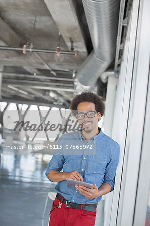 Portrait of confident casual businessman using digital tablet in office