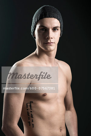 Close-up portrait of young man wearing toque, studio shot on black background