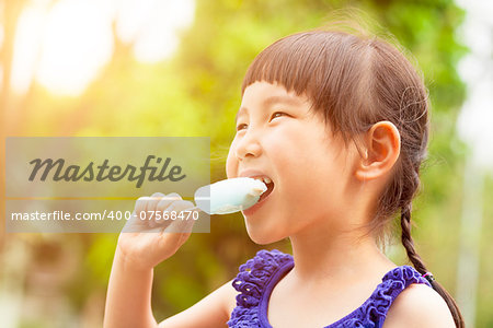 happy little girl eating popsicle at summertime with sunset