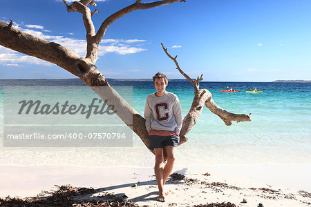 Smiling teen boy on a tropical beach in summer for  relaxing vacation or fun filled leisure on a beautiful sunny day, NSW Australia