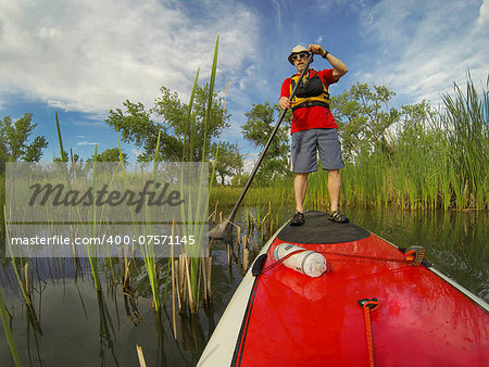 senior male paddler enjoying workout on stand up paddleboard (SUP), calm lake in Colorado, spring colors
