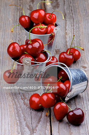 Tin Buckets with Ripe Sweet Cherries isolated on Rustic Wooden background