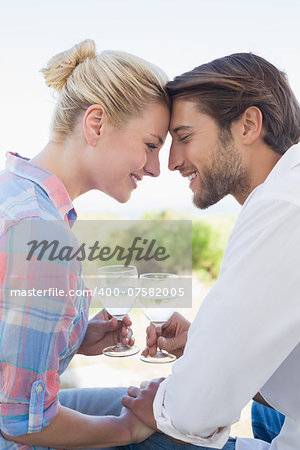 Happy young couple sitting in the garden enjoying wine together on a sunny day