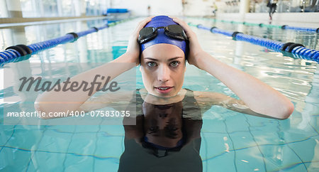 Fit swimmer in the pool smiling at camera at the leisure center