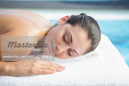 Calm brunette lying on massage table poolside outside at the spa