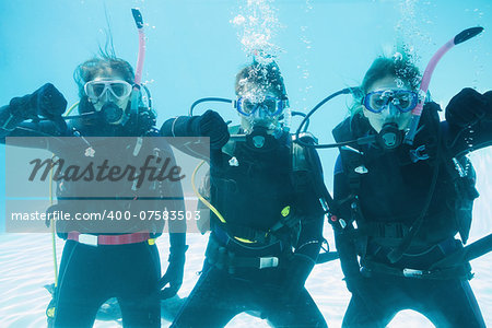 Friends on scuba training submerged in swimming pool showing thumbs down  on their holidays