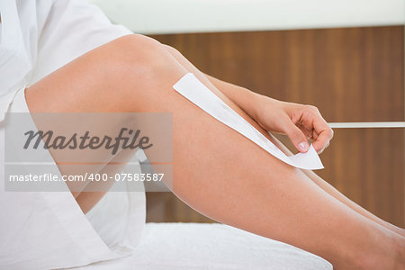 Woman waxing her legs herself in the health spa