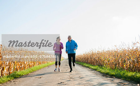 Adult couple running on country road, Germany