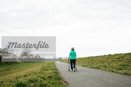 Backview of senior woman walking along path using walker in nature, Germany Backview of senior woman walking along path using walker in nature, Germany