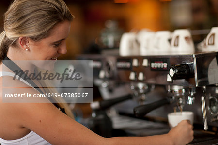 Young female waitress preparing coffee in cafe