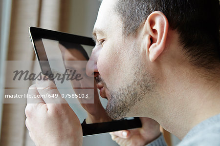 Mid adult man kissing screen of digital tablet