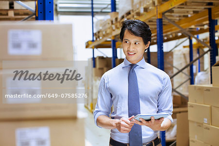 Mid adult male manager using digital tablet in distribution warehouse